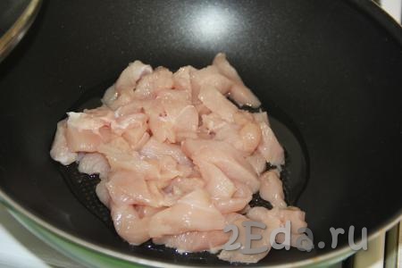 В сковороде с высокими бортиками (или в сковороде вок) разогреть растительное масло, выложить куриное филе, нарезанное на брусочки (или кубики).