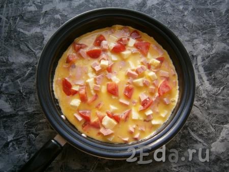 Вылить смесь на разогретую с растительным маслом сковороду и жарить омлет с колбасой, помидорами и сыром на небольшом огне под закрытой крышкой минут 10.