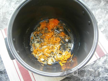 2-3 столовые ложки растительного масла влить в чашу мультиварки, выложить натёртую на крупной тёрке морковь и лук, нарезанный небольшими кусочками, выставить на 15 минут программу "Жарка". Во время обжаривания несколько раз овощи перемешать.