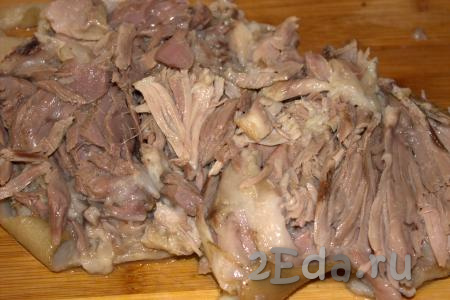 Готовую свиную рульку достать из бульона, выложить на рабочую поверхность. Сделать на рульке продольный надрез, отделить мясо от кости, разложить в пласт (если есть крупные кусочки мяса, разрезать их ножом).