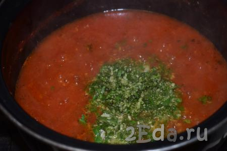 Измельчённые чеснок, базилик и петрушку выкладываем в кастрюлю с томатной массой и перемешиваем.