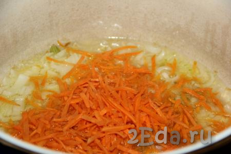 Затем в кастрюлю с луком выложить натёртую на крупной тёрке морковь и обжаривать овощи минут 5, не забывая иногда помешивать.