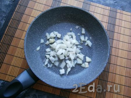 На сковороду вливаем немного растительного масла, выкладываем очищенный лук,  нарезанный на небольшие кубики. 