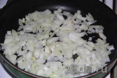 В сковороду добавить немного растительного масла, выложить очищенный и мелко нарезанный лук. Обжарить лук до мягкости на среднем огне, помешивая.