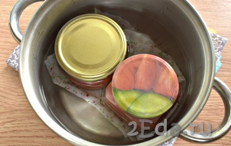 Застилаем дно кастрюли, в которой будете стерилизовать баночки с соусом, тканевой салфеткой (или сложенным в 2-3 раза полотенцем). Ставим в эту кастрюлю поверх салфетки (или полотенца) банки с томатным соусом, вливаем тёплую воду, чтобы она была по "плечики" банок. Ставим кастрюлю с баночками на средний огонь, а после закипания стерилизуем банки с соусом на небольшом огне минут 10.