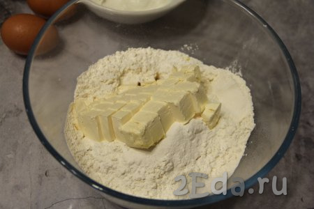 Муку и разрыхлитель всыпать в глубокую миску, добавить холодный маргарин (или сливочное масло), нарезанный на небольшие кусочки. 