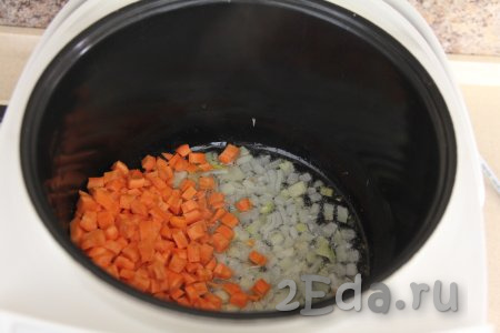 К обжаренному луку выложить морковь, нарезанную на мелкие кубики (или натёртую на крупной тёрке). Обжаривать овощи, не закрывая крышку мультиварки, 3-4 минуты, иногда перемешивая.