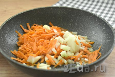 Очищаем лук и морковку. Нарезаем луковицу достаточно мелко, натираем на крупной тёрке морковку и выкладываем на сковороду, в которой обжаривался картофель, перемешиваем овощи и обжариваем их на среднем огне, иногда помешивая, в течение 5 минут.