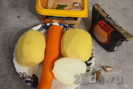 Подготовить продукты для приготовления сырного супа с чечевицей. Картошку, лук, чеснок и морковь почистить. Очищенный картофель, чтобы не потемнел, пока залить полностью водой.