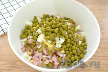 Зелёный консервированный горошек сначала откидываем на сито. Когда вся жидкость сольётся, выкладываем горошек в миску с салатом.