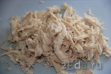 Куриную грудку сварить в подсоленной воде до готовности (в течение 25-30 минут) и остудить. Нарвать куриное мясо на длинные волокна.