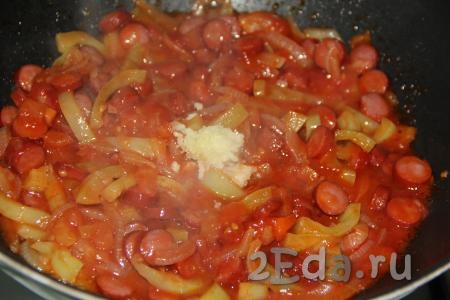 Очищенный чеснок, пропущенный через пресс, выложить на сковороду с овощами и колбасой, добавить соль и специи по вкусу, хорошо перемешать.
