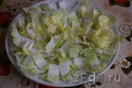 Далее приступим к сборке салата "Цезарь". На большое плоское блюдо для подачи салата выкладываем китайскую капусту, нарезанную на средние квадратики.