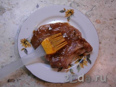 Каждый стейк из свинины обильно смазать с двух сторон подготовленным соусом-маринадом.