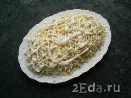 Поверх сыра равномерно распределить натертые на крупной терке вареные яйца, немного посолить, сделать сеточку из майонеза.
