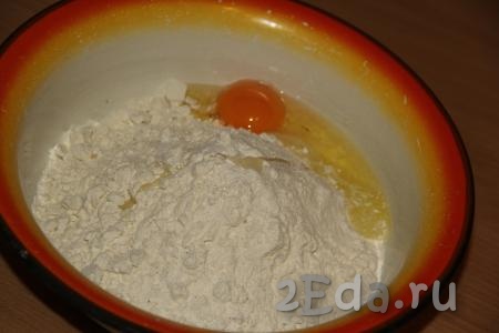 В получившуюся мучную смесь добавить яйцо, влить минералку и растительное масло, вначале вилкой, а затем руками замесить тесто.