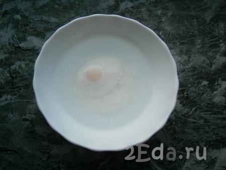 Поместить тарелку с яйцом в микроволновку, выставить время 2 минуты при мощности 700 Ватт. За это время белок свернется и окутает желток. Желток, полностью окутанный белком, останется жидким.