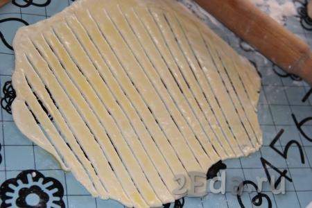 Разрезать раскатанное тесто на тонкие полоски, не дорезая до конца (как на фото).