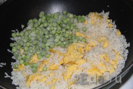 Слегка перемешать рис с яйцами и сразу добавить горошек (предварительно размораживать горошек не нужно).