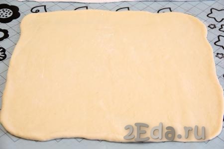 Готовое дрожжевое тесто хорошо обмять, накрыть полотенцем и дать "отдохнуть" 30 минут. Затем на столе, присыпанном мукой (или на силиконовом коврике), раскатать тесто скалкой в прямоугольный пласт.