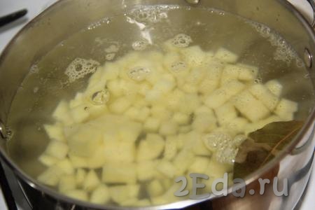 Картофель, лук и морковь очистить. Нарезать картошку на кубики. В кипящую воду выложить картофель и лавровый лист, варить 10 минут с момента закипания на небольшом огне.