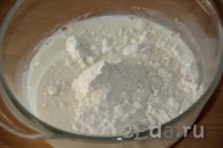 По прошествии времени в глубокую миску влить оставшееся тёплое молоко, добавить 2 столовые ложки муки и 1 столовую ложку сахара, перемешать ложкой молочную массу до однородности.
