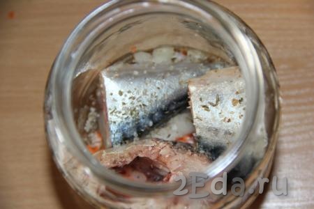 На дно банки поместить немного лука и моркови, затем выложить пару кусочков скумбрии, посолить, добавить специи для рыбы.