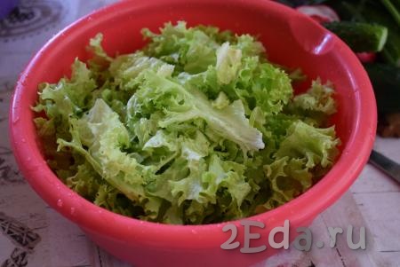 Розетку листового салата разделить на листочки и очень тщательно промыть от земли. Далее обсушить листья салата и нарвать на средние кусочки. Кусочки салата отправить в глубокую миску.