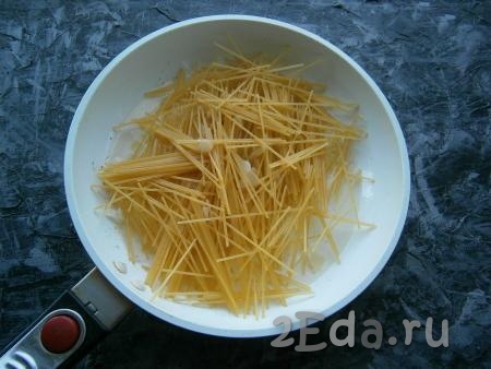 Лук обжарить, иногда помешивая, до мягкости и легкой золотистости. В сковороду выложить спагетти, немного перемешать их с луком.