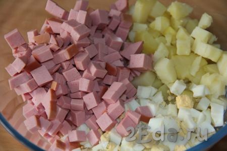 Варёную колбасу нарезать на кубики, примерно, такого же размера, как нарезали картошку и яйца. Выложить колбасу к картофелю и яйцам.