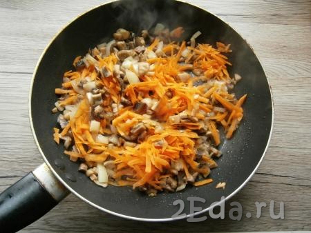 Обжаривать грибы с луком на среднем огне, помешивая, около 5-7 минут, после чего добавить в сковороду натертую на крупной терке очищенную морковь.