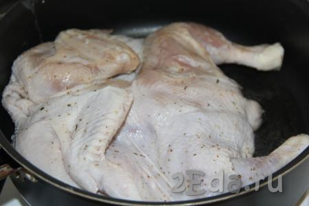 В подходящую по диаметру сковороду влить растительное масло и разогреть. Выложить цыплёнка в сковороду кожей вверх.