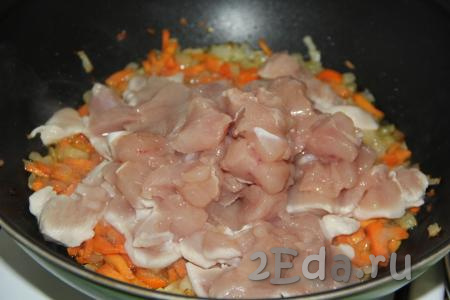 Куриную грудку нарезать на кубики и выложить в сковороду к обжаренным овощам.