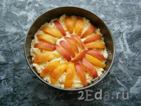 Персики нарезать на дольки и выложить их кожурой вверх, вдавливая в тесто.