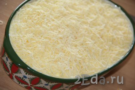 На мелкой тёрке натереть сыр и выложить пышной шапкой поверх салата.
