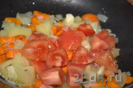Далее в сковороду добавить помидор, очищенный от кожуры и нарезанный средними кубиками, хорошо перемешать и тушить овощи 3-5 минут на медленном огне, помешивая.