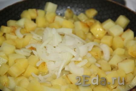 По истечении времени выложить к картошке очищенный и нарезанный полукольцами лук, посолить по вкусу. Жарить ещё 5 минут, иногда перемешивая.