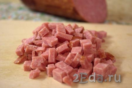 Нарезать копчёную колбасу на кубики среднего размера.
