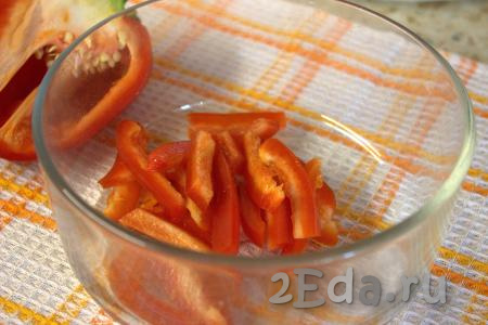 Удалить из болгарского перца перегородки и семена, а затем нарезать его тонкими брусочками и переложить в миску.