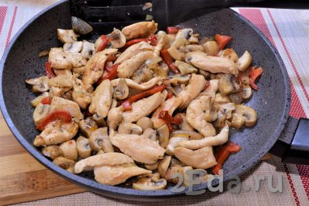 Перемешать и жарить куриное филе с грибами на сковороде на среднем огне, периодически помешивая, около 10 минут. В конце жарки добавить измельчённый чеснок.