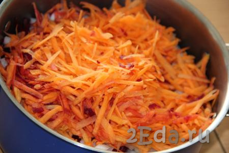 Очищенную и натёртую на крупной тёрке морковь добавить в кастрюлю с луком и свеклой.