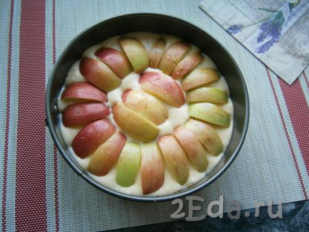 Выложить в форму тесто, сверху разместить дольки яблок без семян кожурой кверху, как на фото.