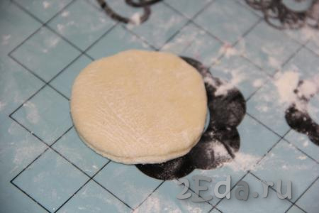 Готовое тесто обмять и переложить на силиконовый коврик, припылённый мукой. Раскатать тесто в пласт толщиной, примерно, 1 см. Вырезать кружочки с помощью стакана.