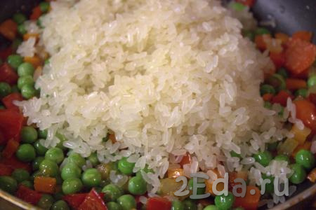 Рис хорошо промыть в нескольких водах. Промытый рис добавить в сковороду с овощами, перемешать, чтобы всё масло впиталось в рис.