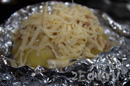 Готовую картошку-гармошку с беконом достать из духовки. Фольгу аккуратно развернуть и посыпать каждую картофелину сыром, натёртым на мелкой тёрке, и измельчённым укропом.