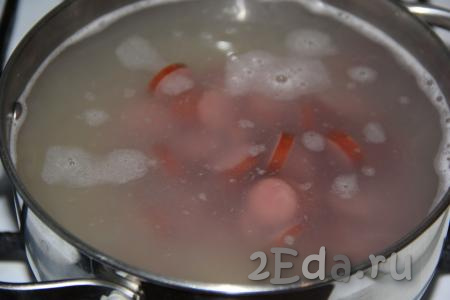 Когда картошка с рисом проварятся минут 10, добавить в суп нарезанные копчёные колбаски и варить 5 минут.