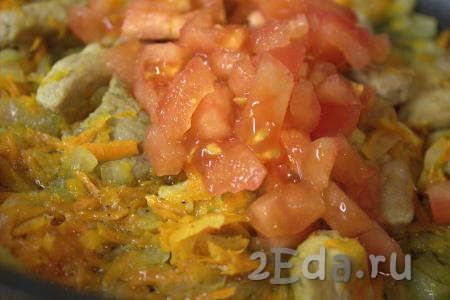 Добавить нарезанный помидор в сковороду к овощам и свинине, перемешать и тушить 2-3 минуты.