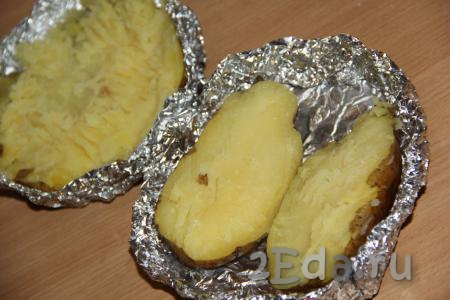 Готовый картофель достать из духовки, развернуть, формируя из фольги, в которой запекалась картошка, круглую тарелочку. Разрезать каждую картофелину на две части.