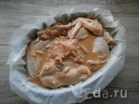 Выложить курицу в застеленную пергаментом форму для запекания, сюда же вылить и соус, оставшийся после маринования мяса.