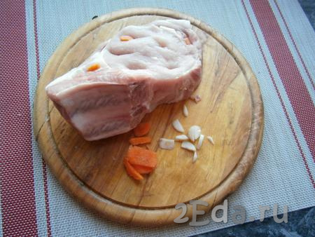 Чеснок и морковь очистить. Кусок свинины вымыть, обсушить и нашпиговать кусочками чеснока и морковки.